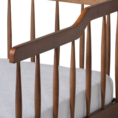 Wooden crib with white mattress on a white background