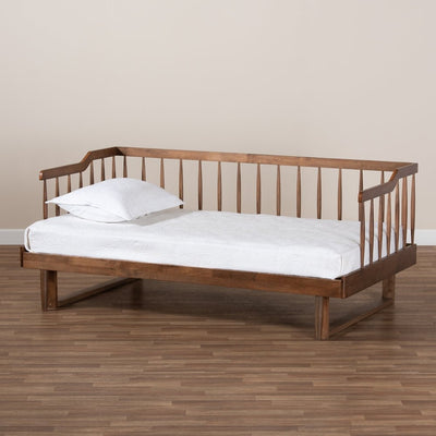 Wooden daybed with white mattress and pillow against a beige wall.