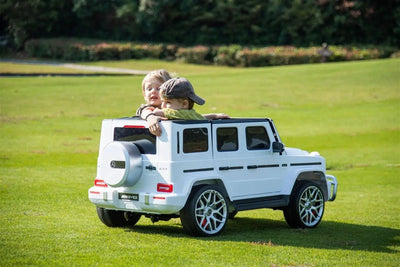 24V white Mercedes Benz G63 AMG 4x4 ride-on car for kids, featuring a realistic luxury SUV design, two seats, LED lights, working doors, and all-terrain wheels.