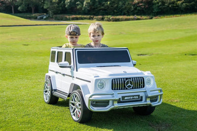 24V white Mercedes Benz G63 AMG 4x4 ride-on car for kids, featuring a realistic luxury SUV design, two seats, LED lights, working doors, and all-terrain wheels.