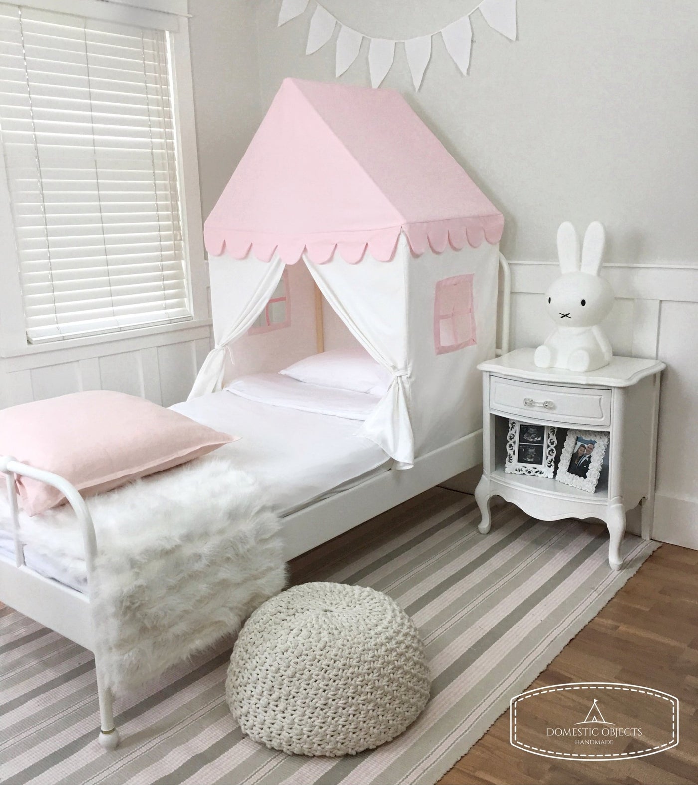 Pink and white children's bed canopy with scalloped edge in a bedroom setting.