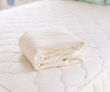 Naturepedic Organic Waterproof Protector Pad on bed – breathable, GOTS certified organic cotton mattress protector for babies and adults.
