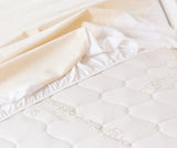 Naturepedic Organic Waterproof Protector Pad on bed – breathable, GOTS certified organic cotton mattress protector for babies and adults.